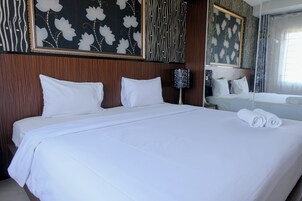 Une chambre d’hôtel avec un grand lit, deux oreillers, une lampe de chevet, un miroir et une fenêtre avec des rideaux.