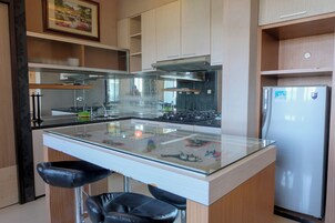Une cuisine moderne dotée d’un îlot central, de tabourets de bar noirs, d’appareils électroménagers en acier inoxydable et de meubles de rangement en bois.