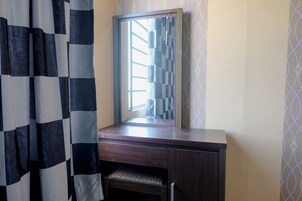 Une salle de bain avec un meuble-lavabo en bois, un miroir et un rideau à motifs.