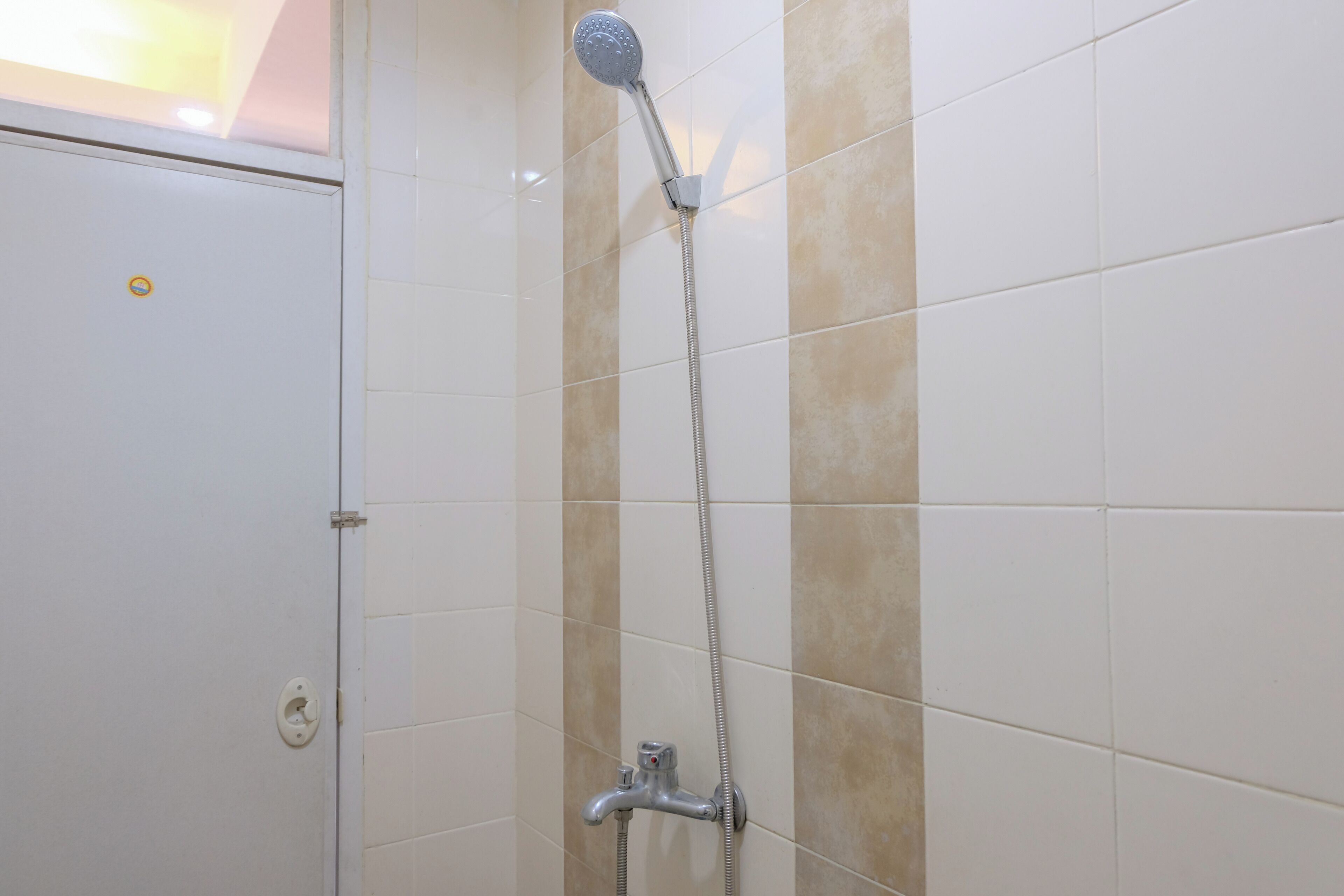 A shower with a handheld showerhead and a wall-mounted faucet.