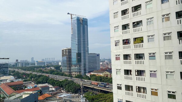 A modern high-rise building with a construction crane, surrounded by a mix of residential and commercial buildings.