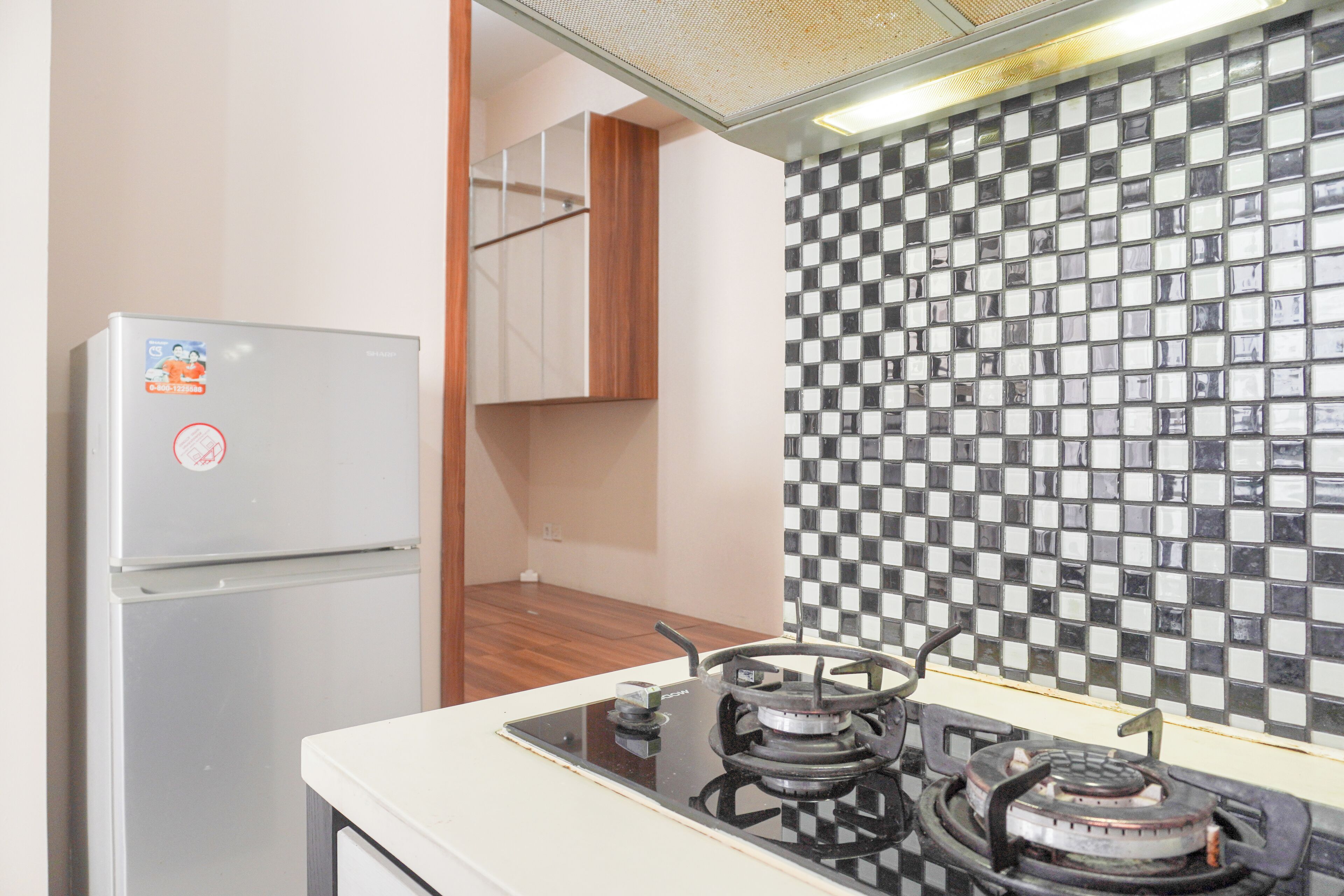 A kitchen with a refrigerator, a gas stove, and a tiled backsplash.