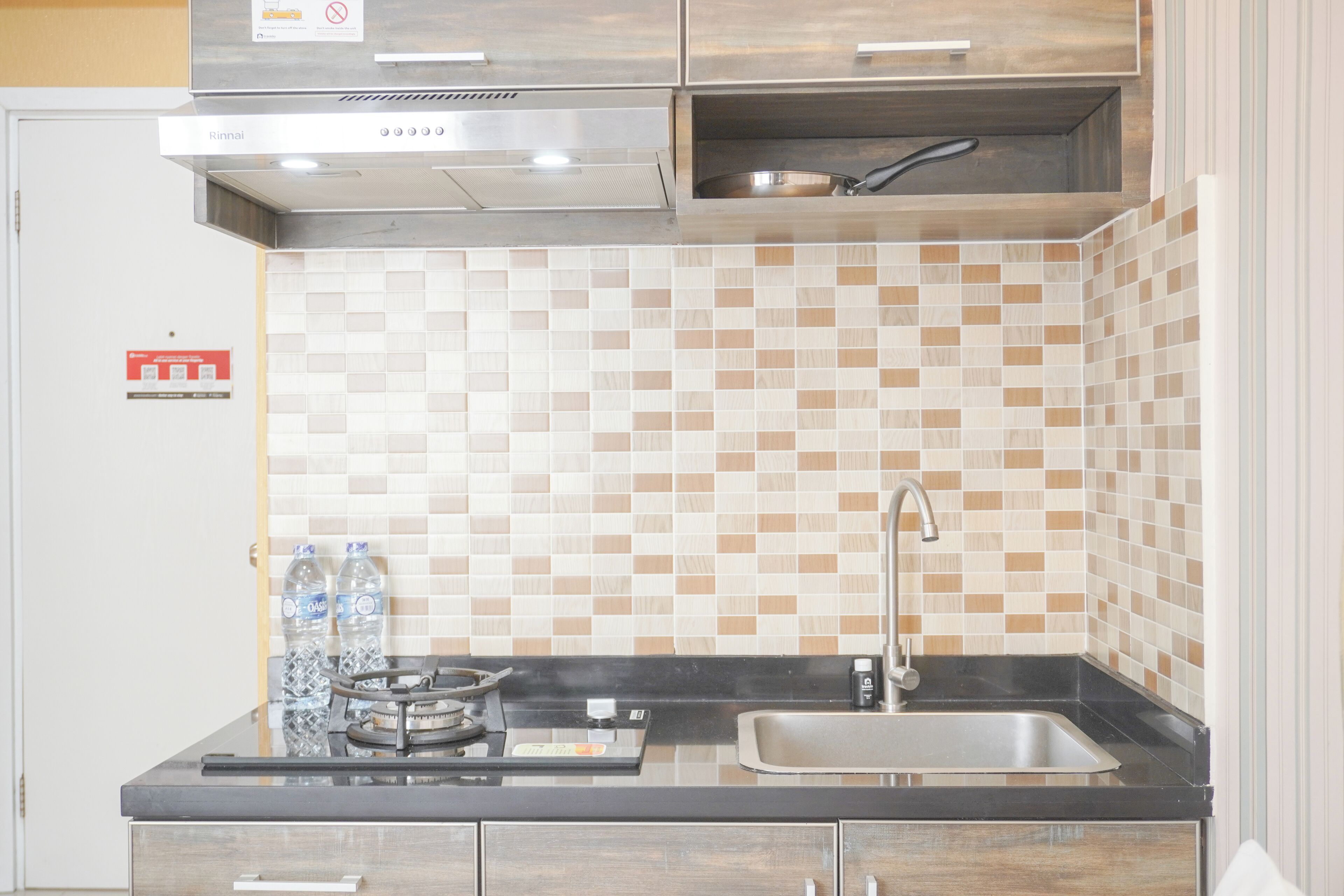 A kitchen with a black countertop, stainless steel sink, and a tiled backsplash.