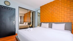 Une chambre d’hôtel comprenant un lit, une armoire, un miroir et un mur orné d’un motif géométrique.