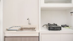 A kitchen with a sink, a kettle, and a kettle holder. - Nice And Tidy 2Br At Bassura City Apartment Near Mall (Jakarta)