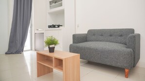 A modern living room with a grey sofa, a wooden coffee table, and a potted plant. - Nice And Tidy 2Br At Bassura City Apartment Near Mall (Jakarta)