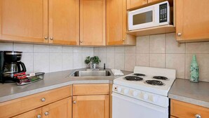 A kitchen with wooden cabinets, a white stove, a microwave, a sink, and a coffee maker.