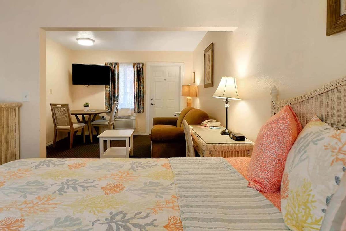 Ein Hotelzimmer mit Bett, Schreibtisch, Stuhl, Fernseher und Lampe.