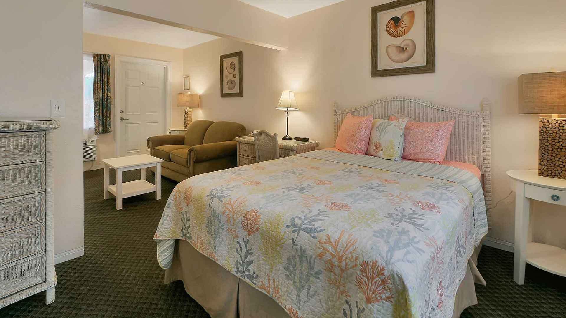 Quarto com cama, uma cadeira, uma mesinha e um armário.