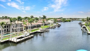 A waterfront property with a swimming pool, docked boats, and a marina. - Luxe Canal Home, Boat Rental, Walk to Cape Harbour (Cape Coral)