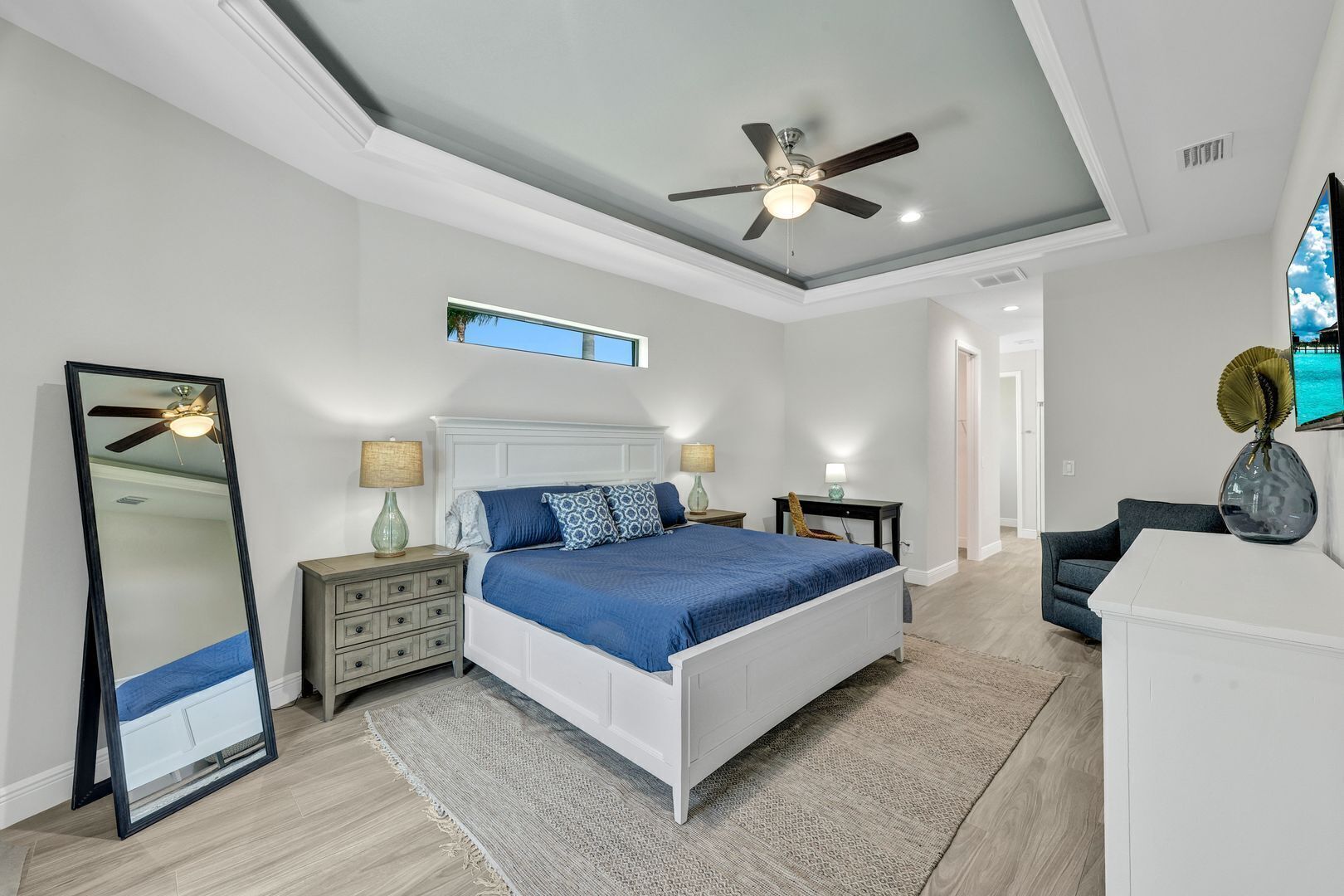 A bedroom with a bed, nightstands, a dresser, a ceiling fan, and a large mirror.