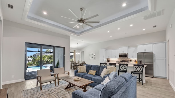 A spacious living room with a blue sofa, wooden coffee table, and a view of a pool and outdoor area. - Luxe Canal Home, Boat Rental, Walk to Cape Harbour (Cape Coral)