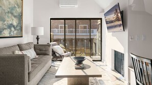A modern living room with a sofa, a coffee table, and a TV mounted on the wall.