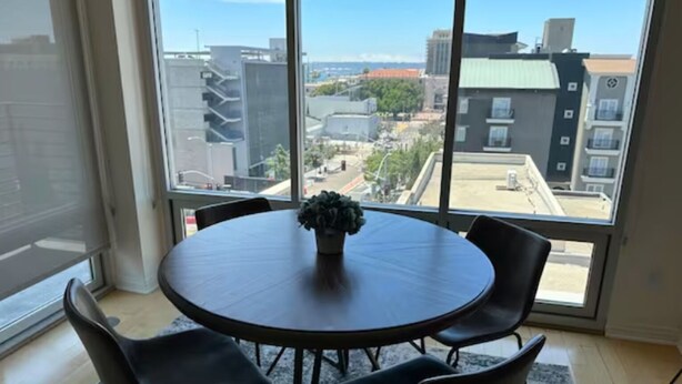 Una mesa redonda con cuatro sillas en una habitación con grandes ventanales que ofrecen vista panorámica de la ciudad.