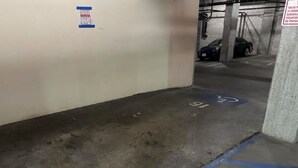 Un aparcamiento con suelos de hormigón, plazas delimitadas y una línea azul que indica un límite.