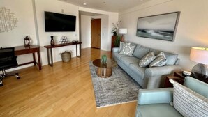 Una sala de estar moderna con un sofá gris, una mesa de centro, un televisor y un cuadro en la pared.