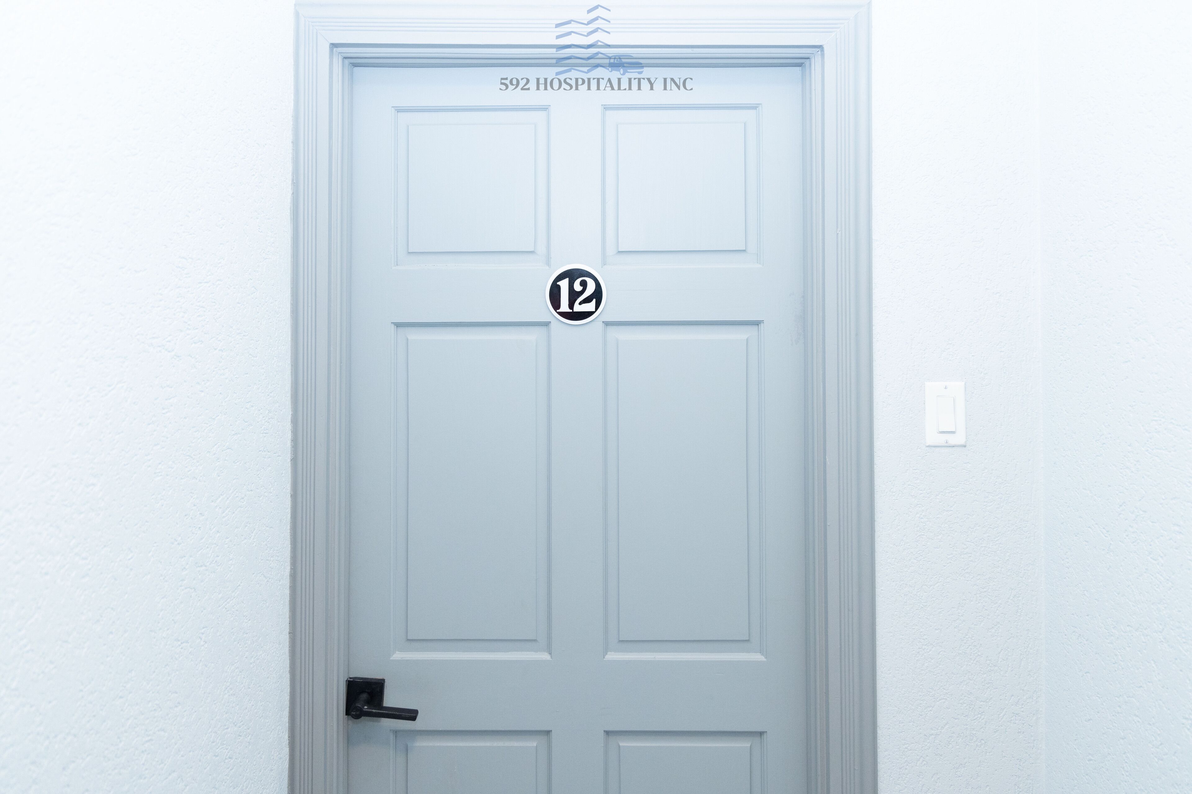 A white door with the number 12 and the text "592 HOSPITALITY INC" above it.