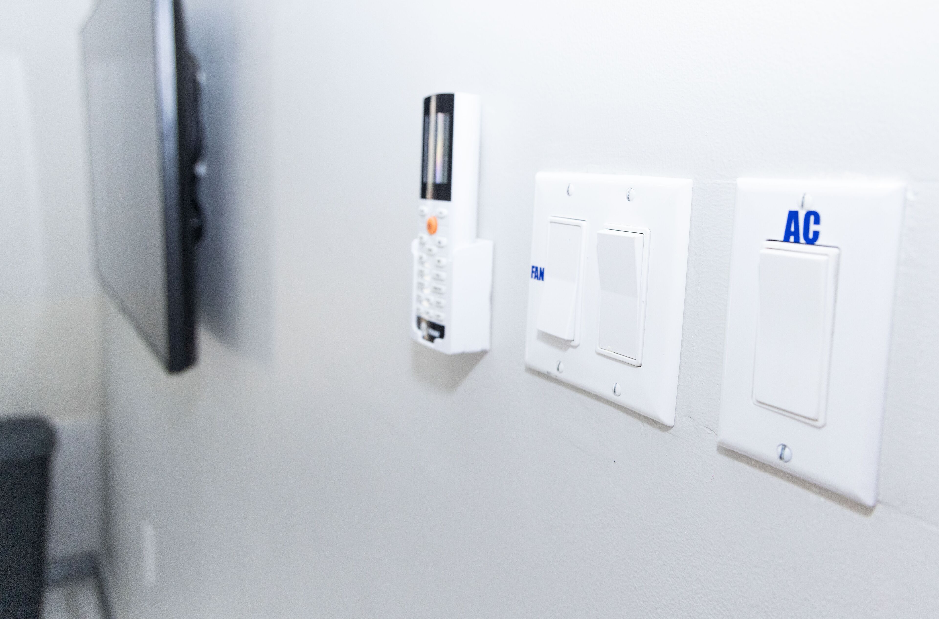 A wall-mounted security system with a keypad and two switches labeled "FAN" and "AC".