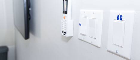 A wall-mounted security system with a keypad and two switches labeled "FAN" and "AC".