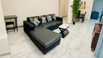 Un salon moderne avec un canapé d’angle, une petite table et une plante en pot.