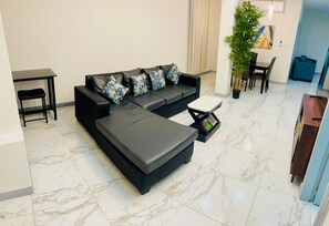 Un salon moderne avec un canapé d’angle, une petite table et une plante en pot.