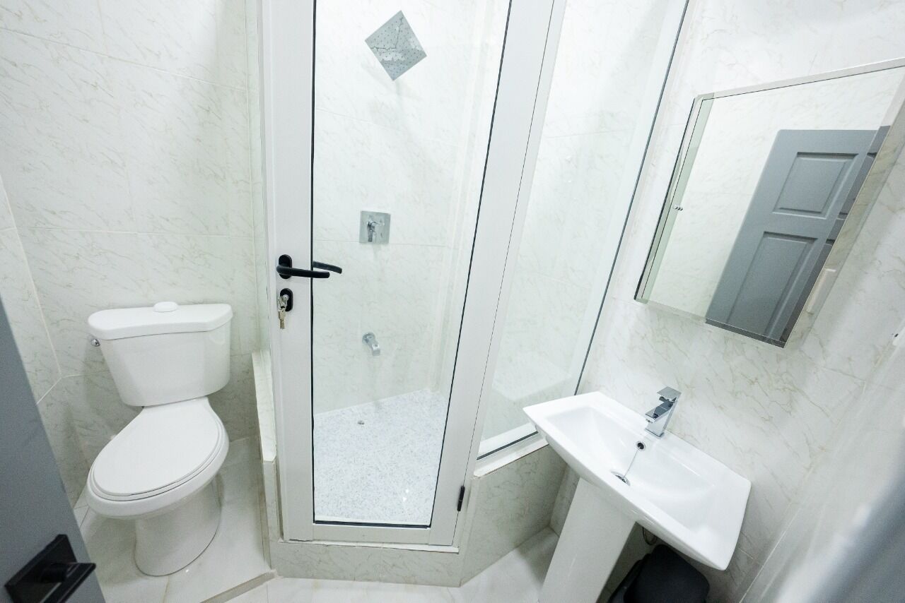 A bathroom with a toilet, a glass-enclosed shower, and a sink.