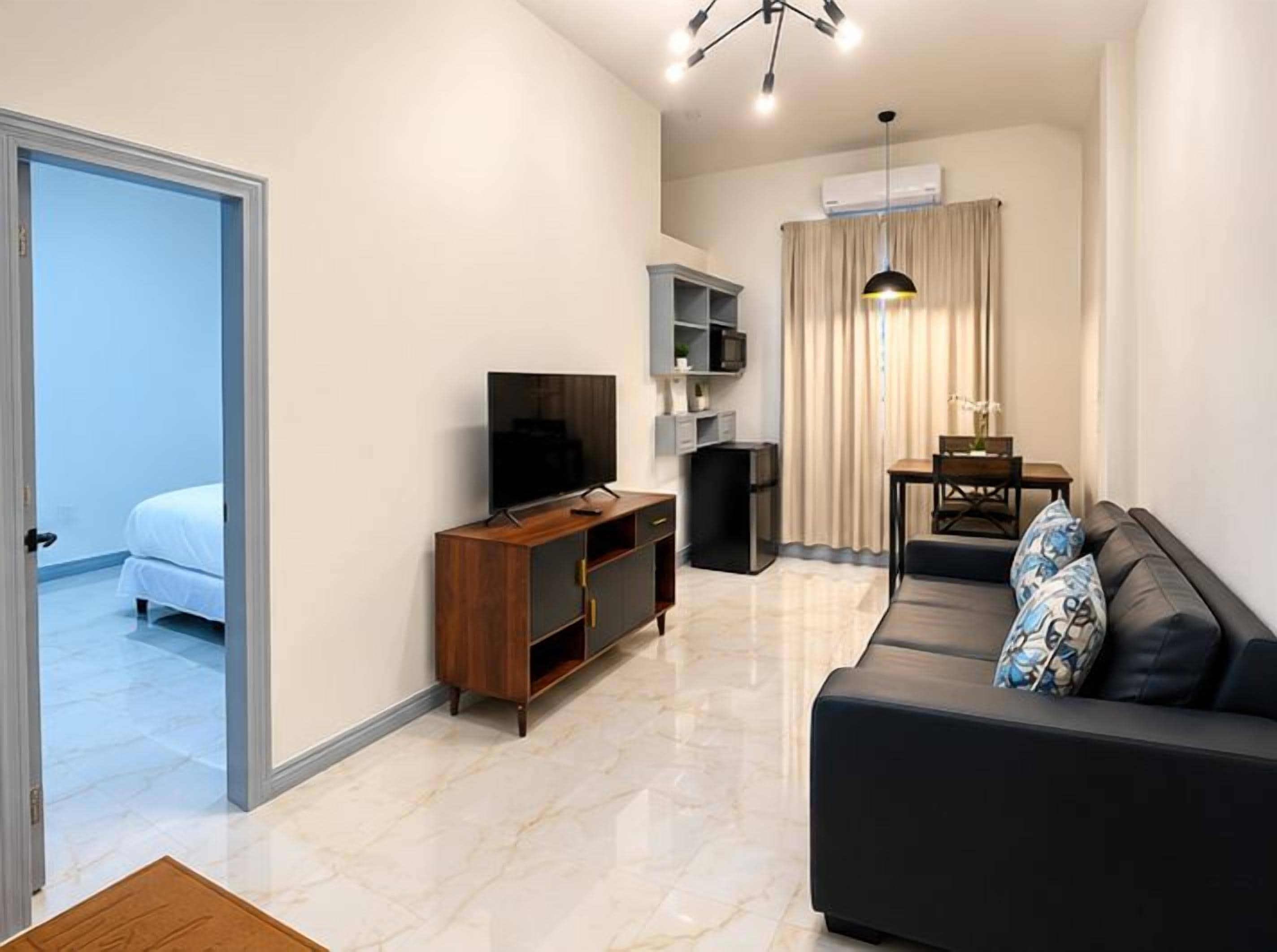 Una sala moderna con sofá, televisión y comedor con mesa y sillas.
