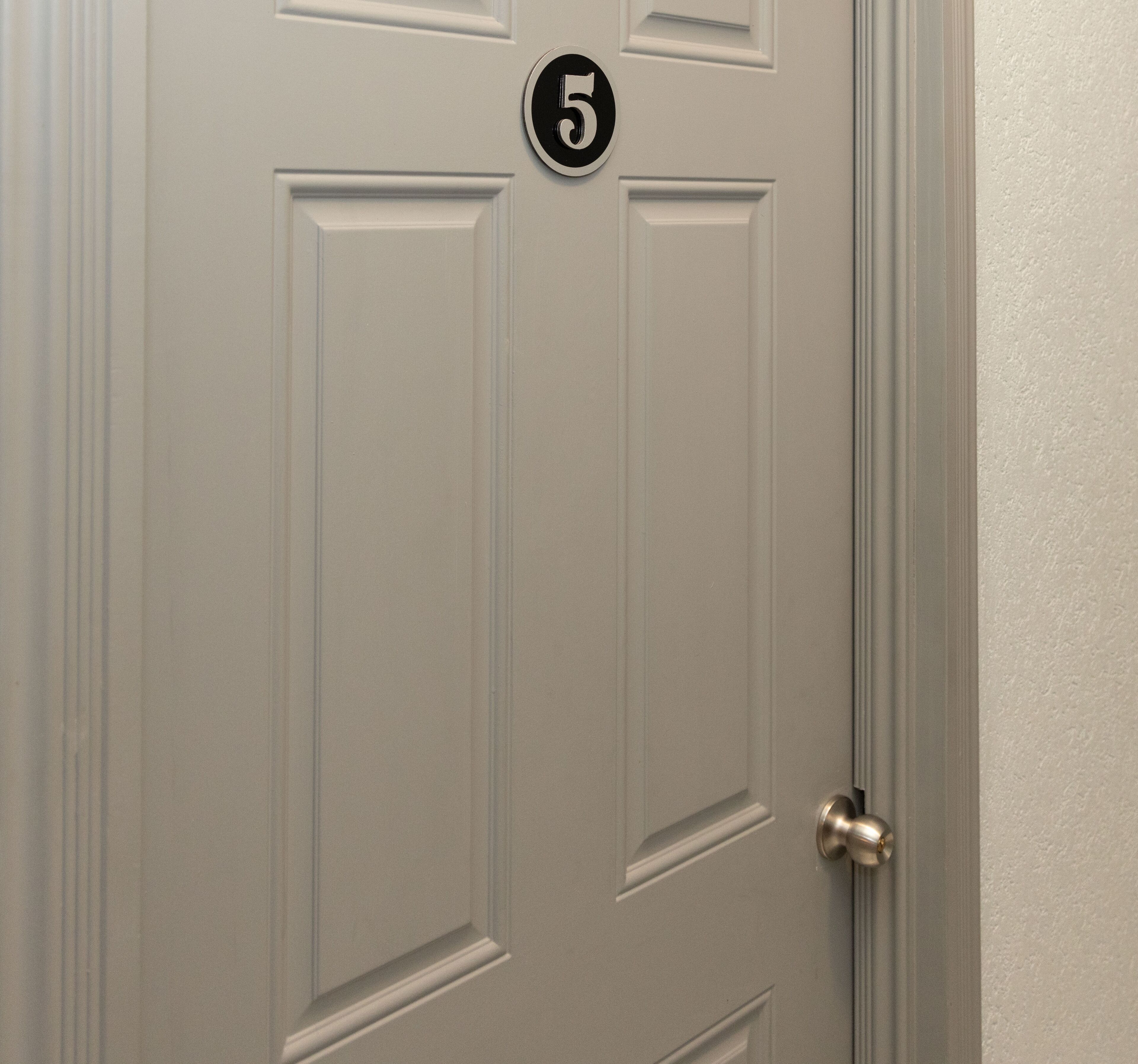 A white door with a number "5" sign above it and a silver doorknob.