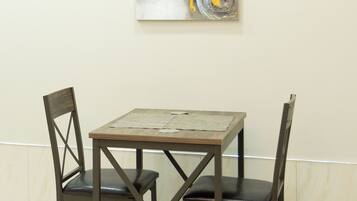 Een eettafel met vier stoelen, een abstract schilderij aan de muur en een marmeren vloer.