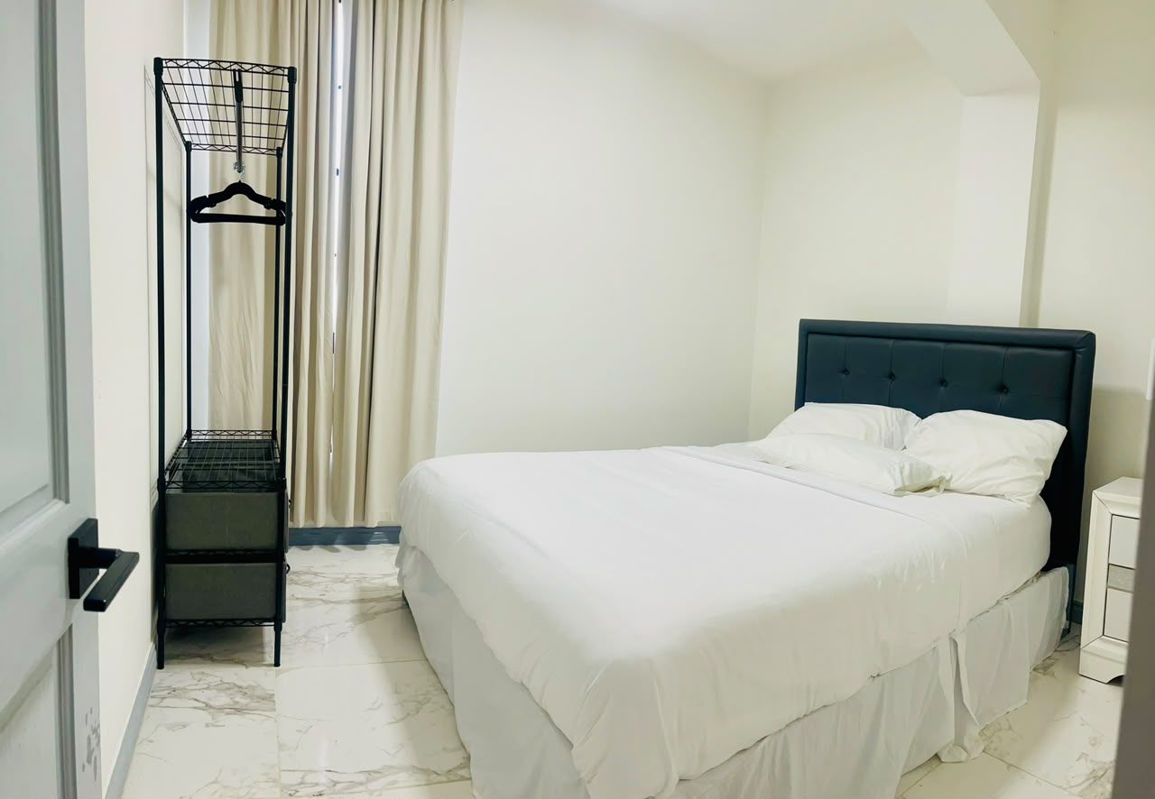Un dormitorio con cama, perchero y puerta.