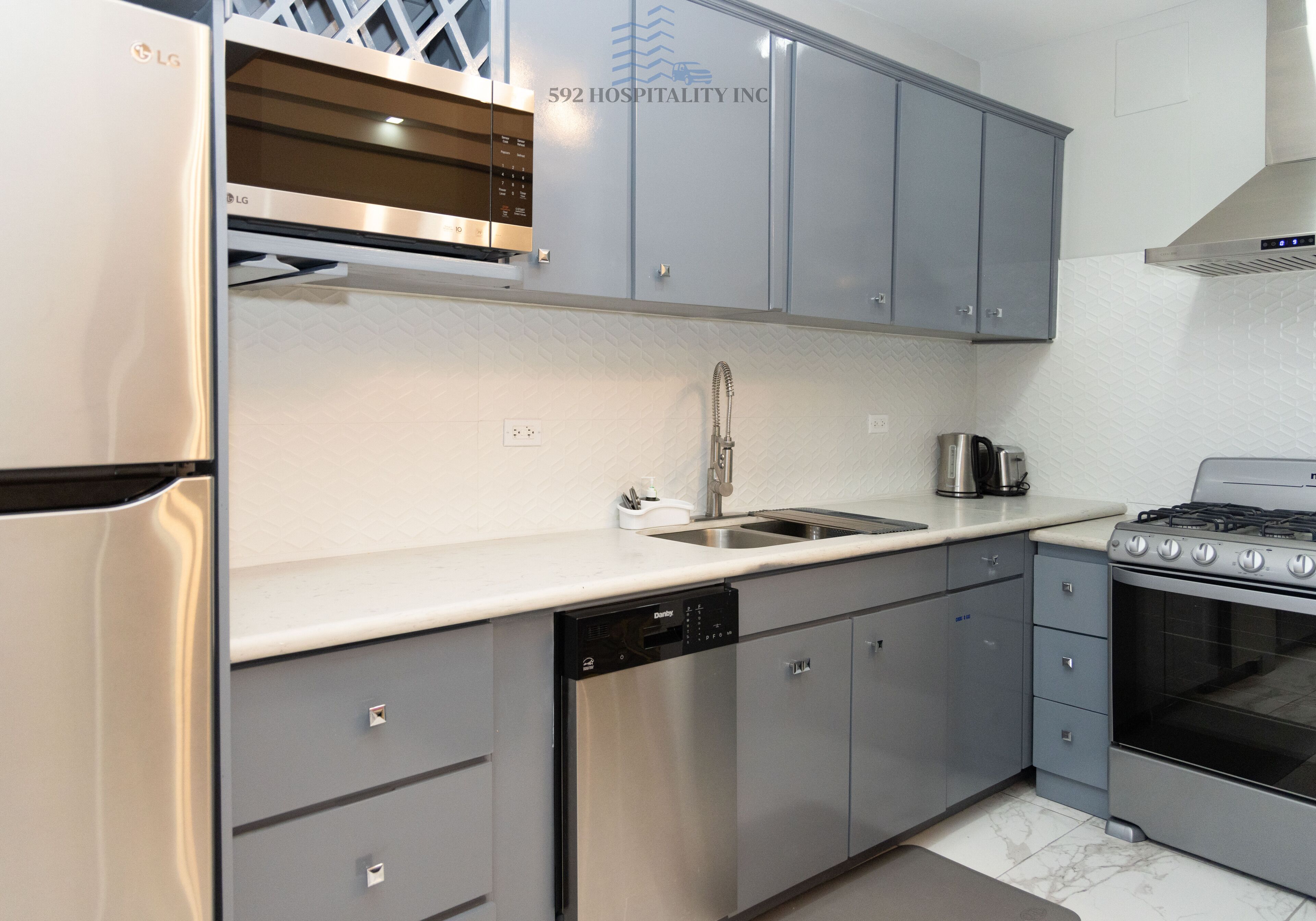 A modern kitchen with grey cabinets, stainless steel appliances, and a dishwasher.