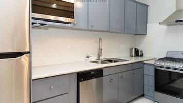 A modern kitchen with grey cabinets, stainless steel appliances, and a dishwasher.