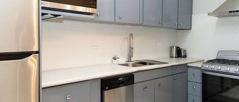 A modern kitchen with grey cabinets, stainless steel appliances, and a dishwasher.