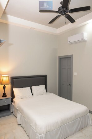 A neatly made bed with white linens, a bedside lamp, a ceiling fan, and an air conditioning unit on the wall. - 592 Hospitality Inc (Georgetown)