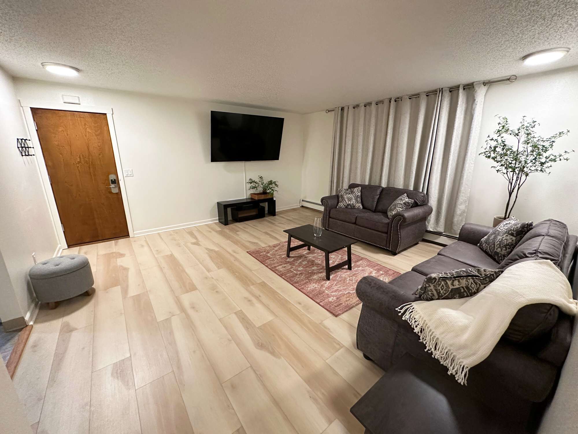 A living room with a sofa, a coffee table, a TV, and a door.