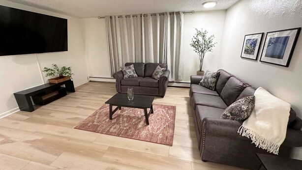 A living room with a flat-screen TV, two sofas, a coffee table, and a potted plant. - Stay Anchorage! Fully Furnished Apartments with GCI RED 2 GIG Internet (Anchorage)