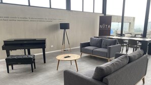 Ein modernes Wohnzimmer mit einem Flügel, einem Sofa, einem Couchtisch und einem großen Fenster mit Blick auf die Stadt.