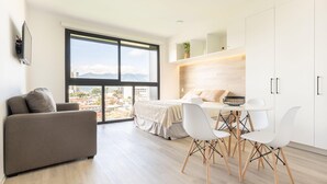 Eine moderne Wohnung mit großem Fenster, Essbereich, Sofa und Bett.