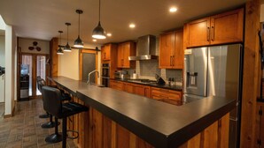 Une cuisine moderne avec des meubles en bois, des appareils en acier inoxydable et un grand îlot central doté de tabourets de bar.