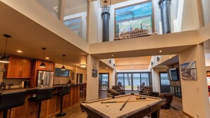 Un grand espace intérieur comprenant une table de billard, un bar et des coins salon.