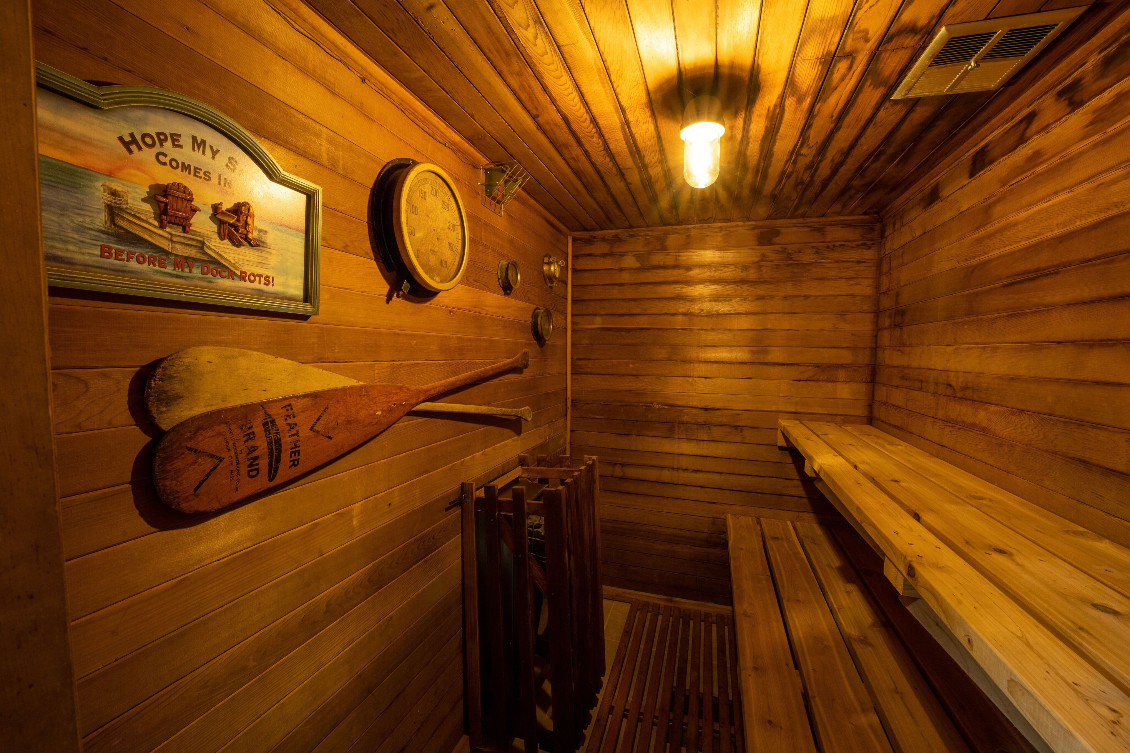 A wooden sauna with benches and a wall-mounted thermometer.