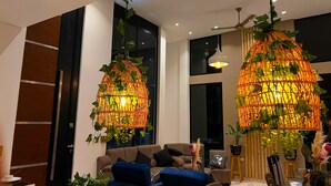 A modern living room with a sofa, a dining table, and two hanging light fixtures with plants. - Carmen de Apicalá (Carmen de Apicala)