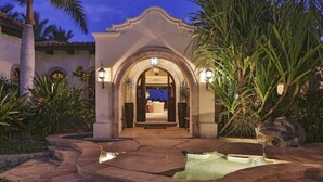 A well-lit entrance with a stone pathway leading to a building, surrounded by tropical plants and a small water feature. - Villa de Lujo en Cabo del Sol Casa Costa (Cabo San Lucas)