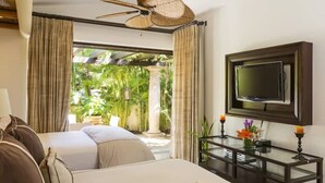 A hotel room with a bed, a TV mounted on the wall, a bedside table with a candle, and curtains. - Villa de Lujo en Cabo del Sol Casa Costa (Cabo San Lucas)