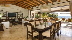 A spacious living area with a dining table, comfortable seating, a television, and a view of the ocean. - Villa de Lujo en Cabo del Sol Casa Costa (Cabo San Lucas)