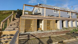 Una casa moderna con una terraza de madera y una escalera que lleva a un balcón.