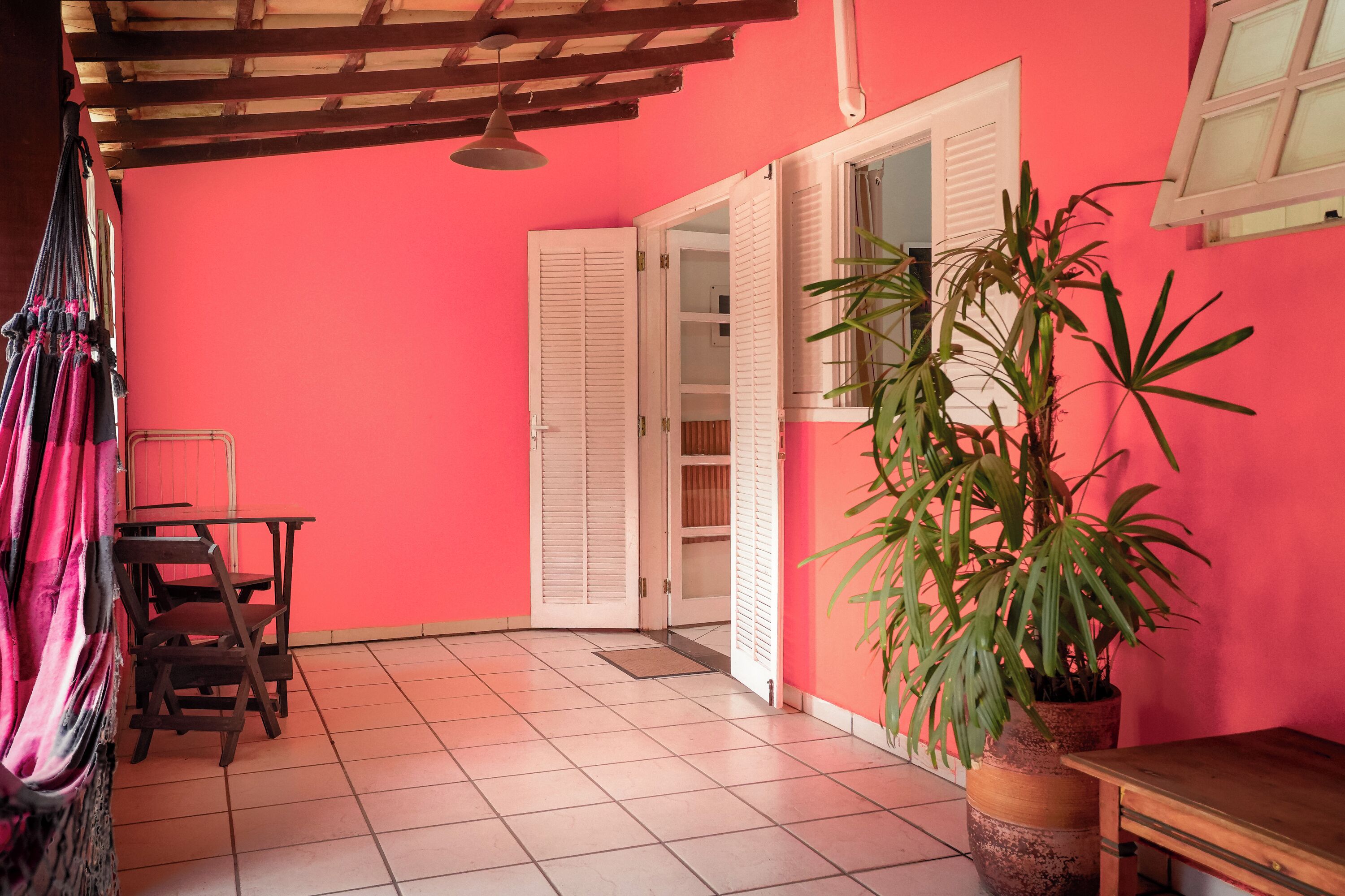 Een kamer met een roze muur, een houten plafond, een kamerplant en een tafel.