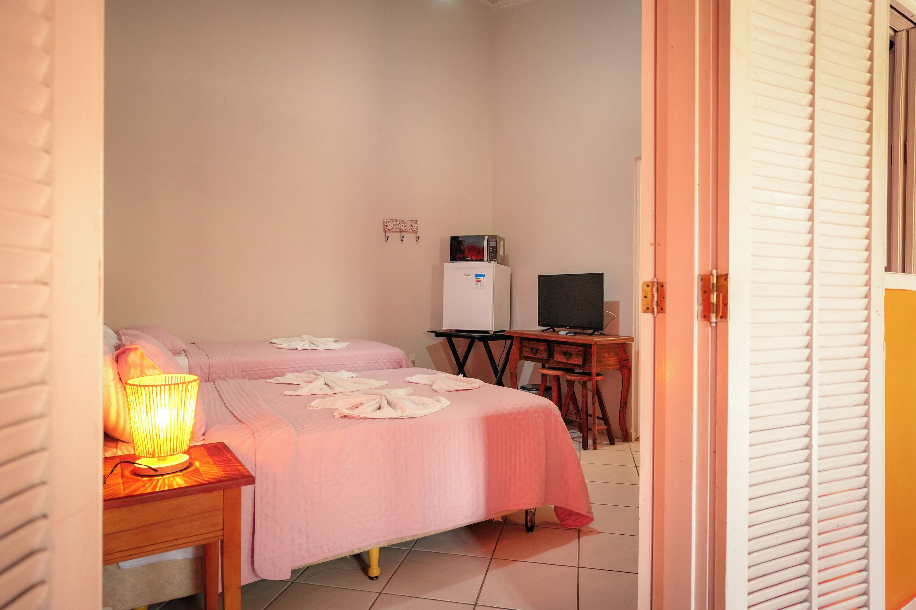 A hotel room with two beds, a desk with a computer, and a television.