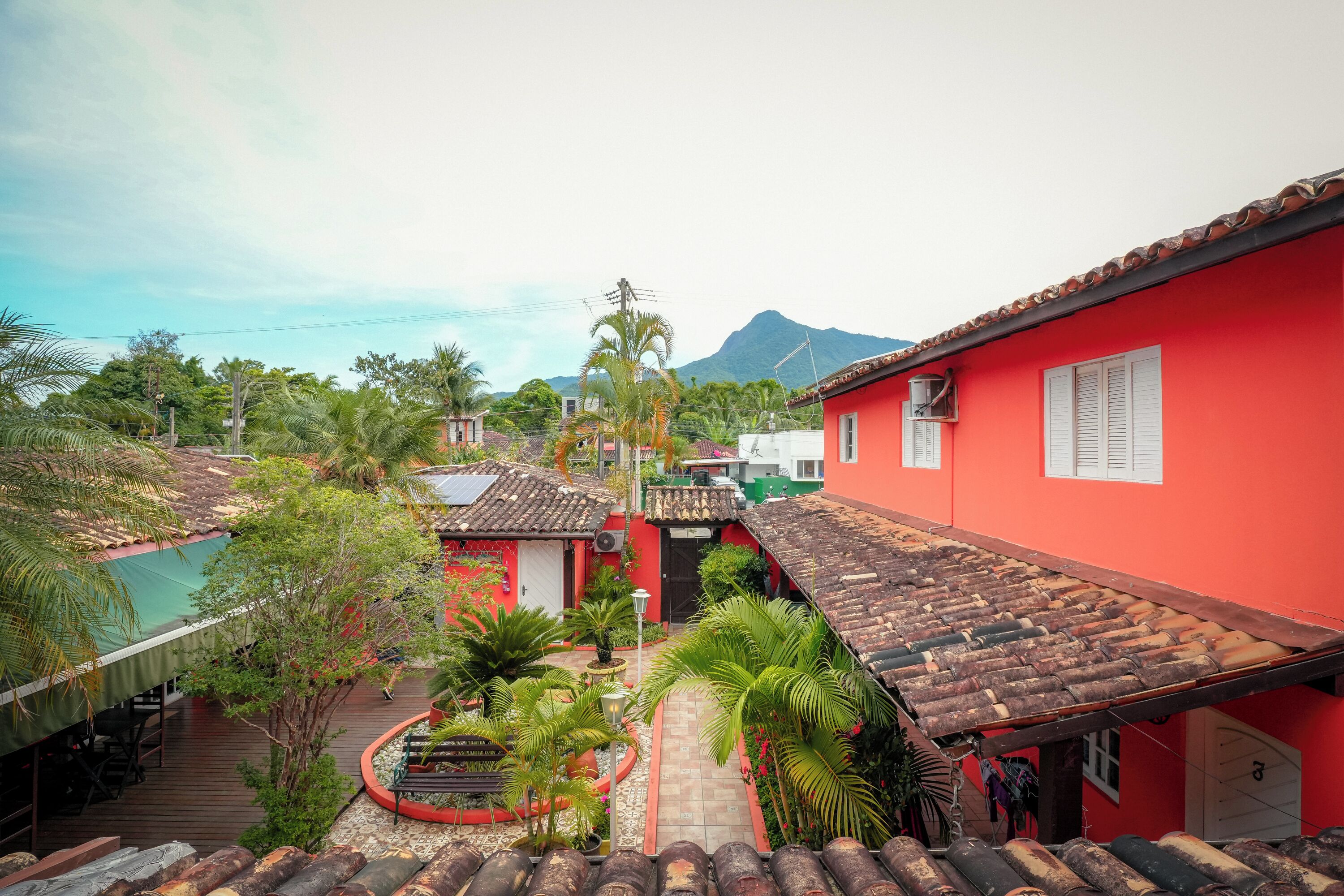 A courtyard with red buildings, a tiled roof, and a mountain in the background.