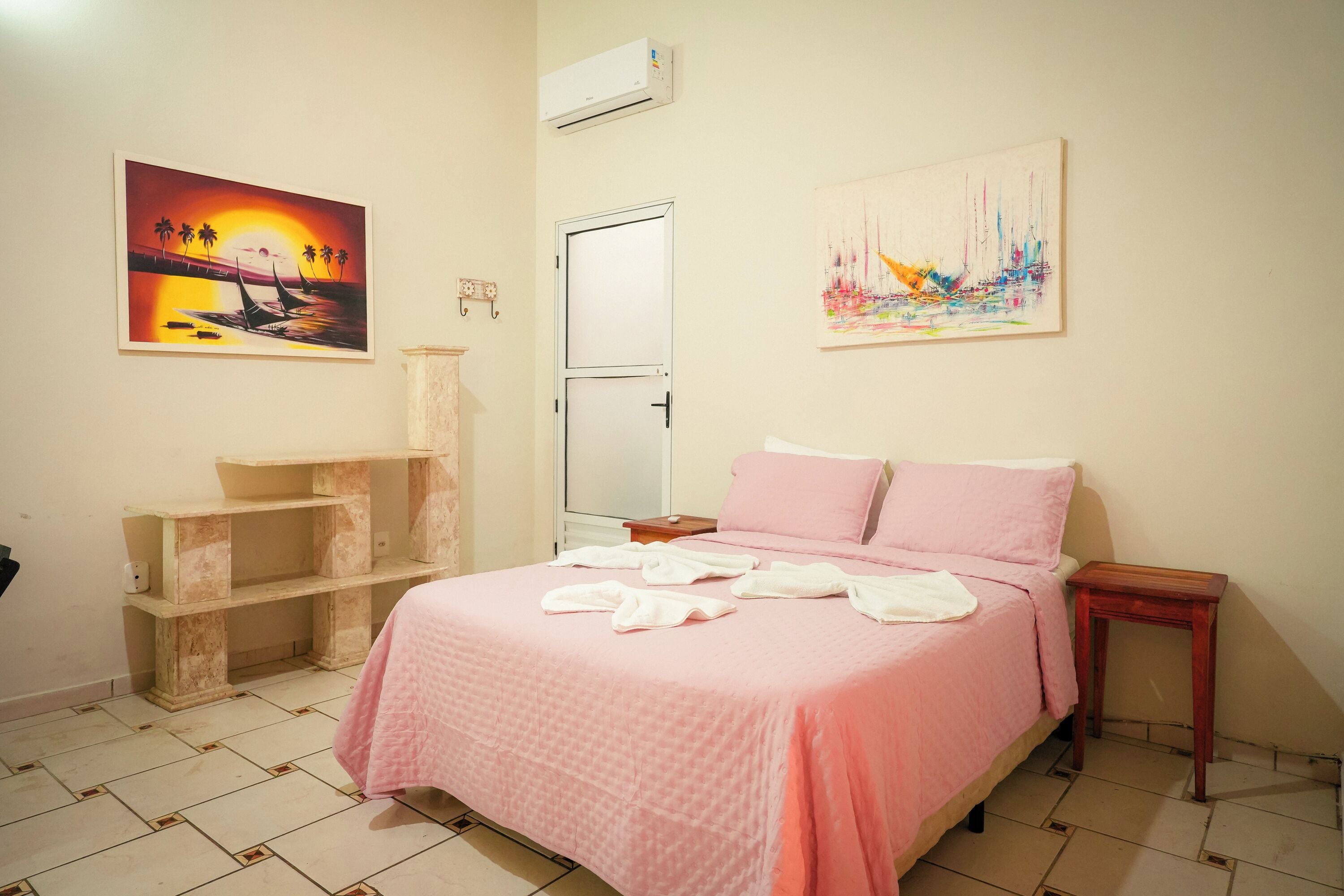 Un dormitorio con una cama, una estantería y dos cuadros en la pared.